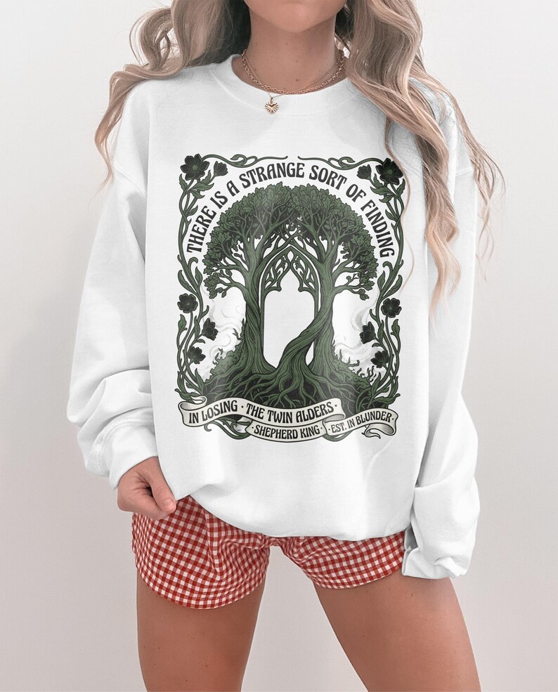 White sweatshirt with "The Twin Alders" art and quote.