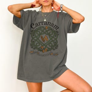 Gray t-shirt with a Celtic knot design, feathers, and text "Carranam".
