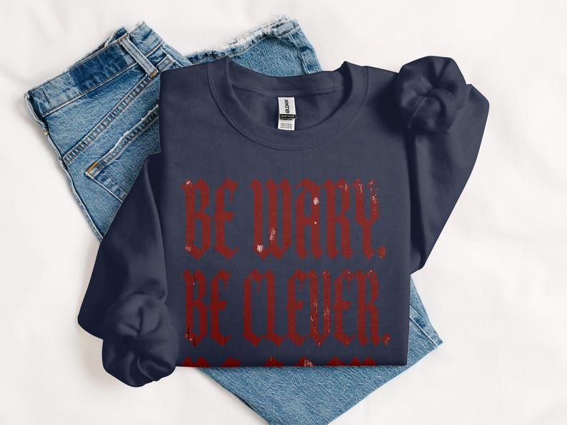 Navy sweatshirt with distressed red text reading "BE WARY. BE CLEVER."