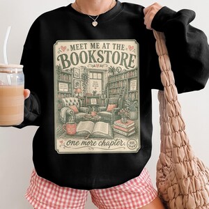Black sweatshirt with "Meet Me at the Bookstore" text and book illustrations.