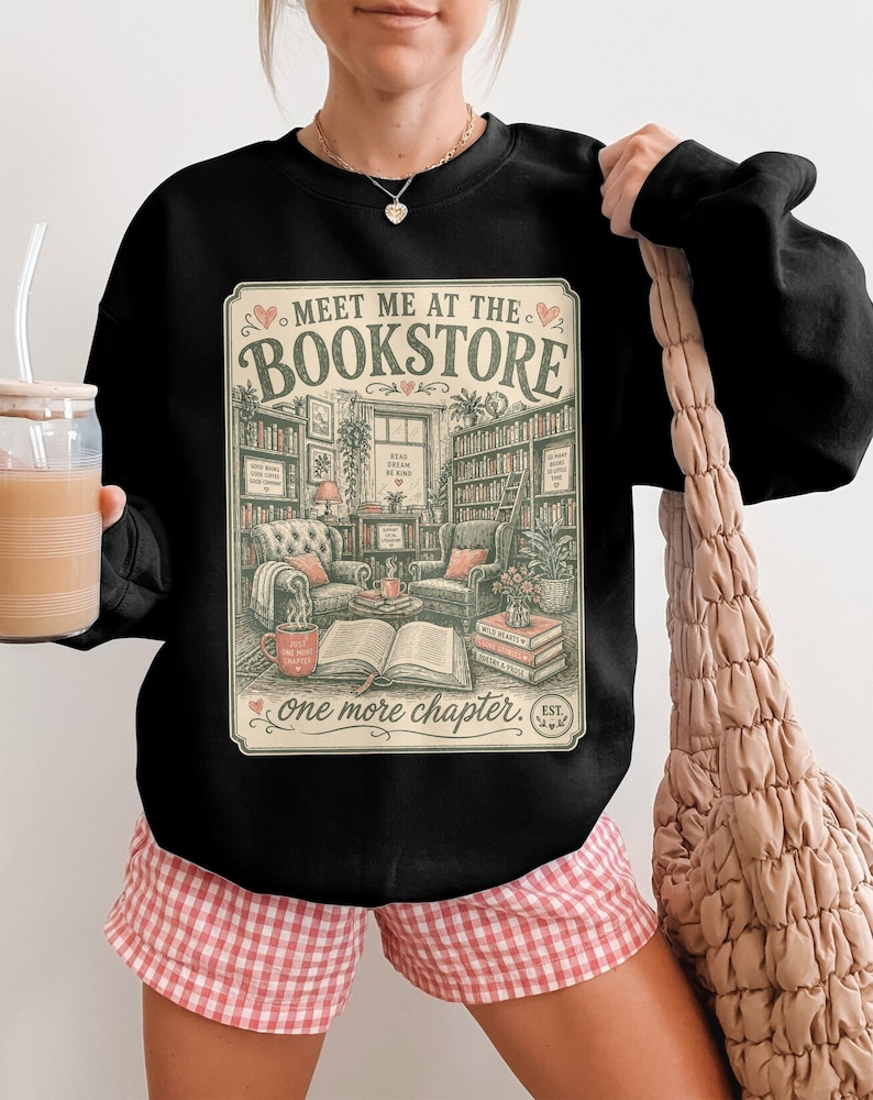 Black sweatshirt with "Meet Me at the Bookstore" text and book illustrations.