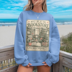 Light blue sweatshirt with "Meet me at the Bookstore" design and book-themed illustrations.