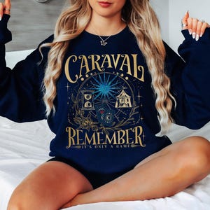 a woman sitting on a bed wearing a blue sweatshirt