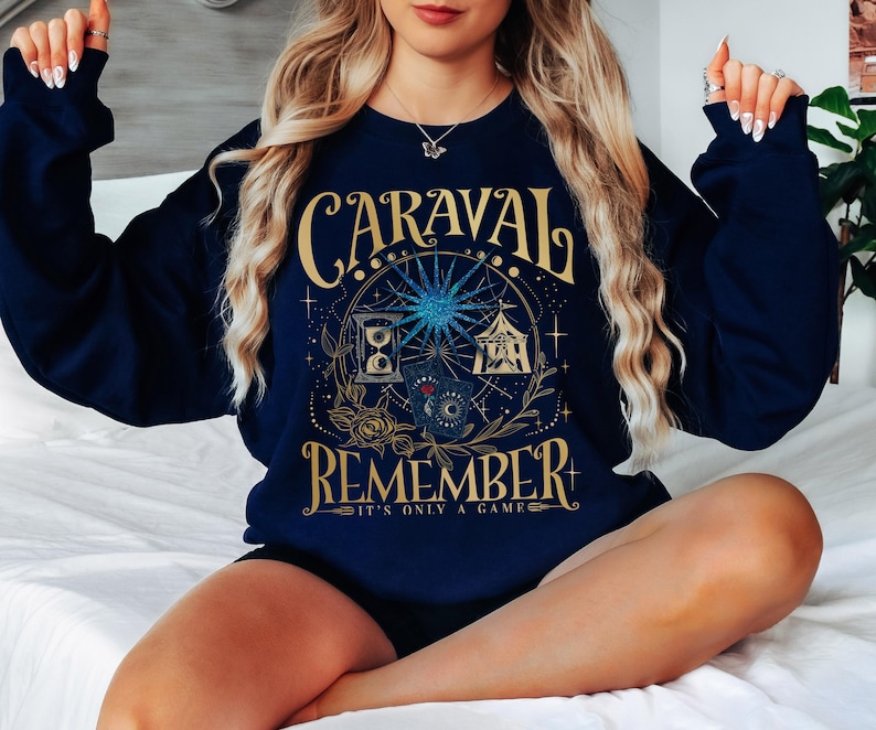 a woman sitting on a bed wearing a blue sweatshirt