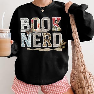 Black sweatshirt with "BOOK NERD" text in floral and distressed letter designs.