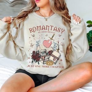 a woman sitting on a bed wearing a sweatshirt