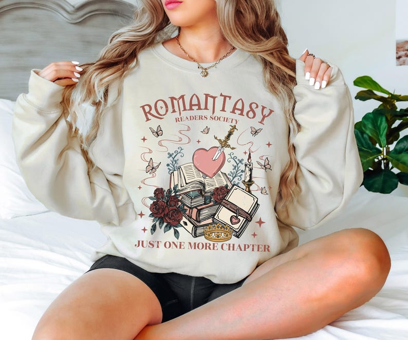 a woman sitting on a bed wearing a sweatshirt