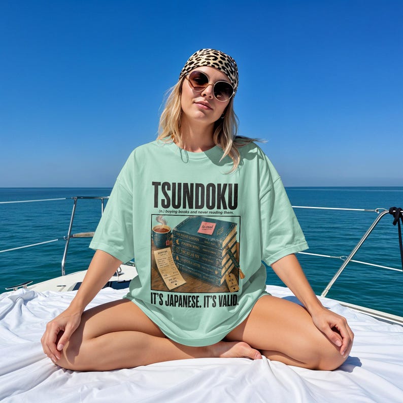 T-shirt with "Tsundoku" text and stacked books illustration.