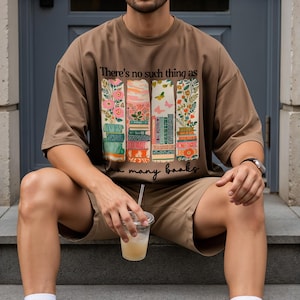 Brown t-shirt with stacked books and butterflies, text "There's no such thing as too many books."
