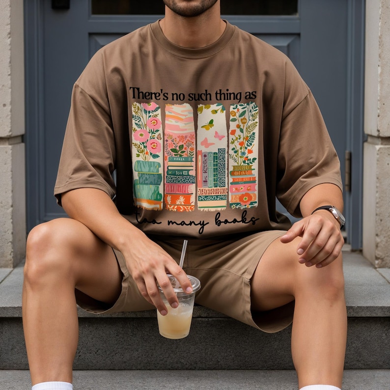 Brown t-shirt with stacked books and butterflies, text "There's no such thing as too many books."