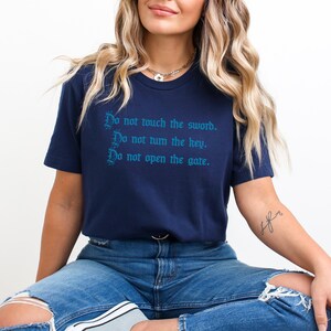 a woman sitting on a stool wearing a t - shirt that says do not touch