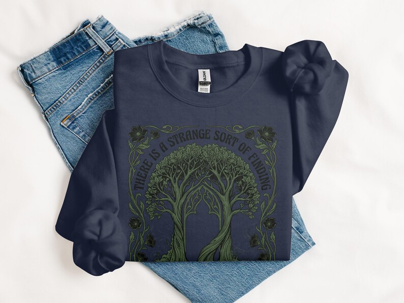 Navy sweatshirt with a green tree design and text "THERE IS A STRANGE SORT OF FINDING".