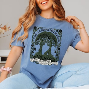 Blue t-shirt with twin trees and text "There is a strange sort of finding in losing".