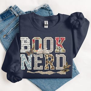 Navy sweatshirt with "BOOK NERD" text design and floral patterns.