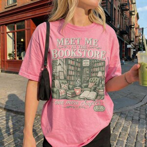Pink t-shirt with "Meet me at the bookstore" graphic and library scene.