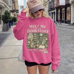Pink sweatshirt with "Meet me at the Bookstore" and book-themed illustration.
