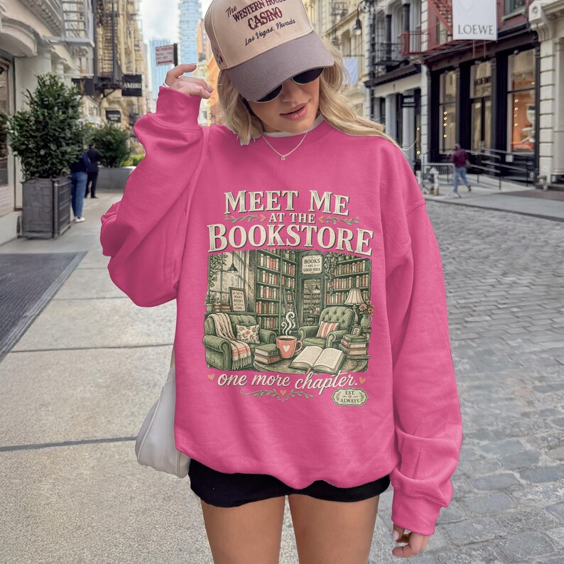 Pink sweatshirt with "Meet me at the Bookstore" and book-themed illustration.