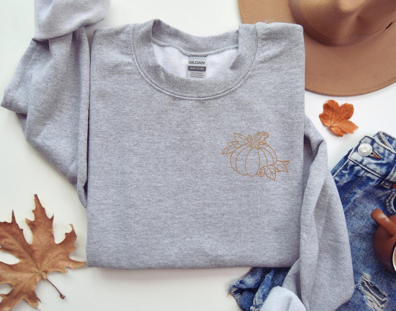 a gray sweater with a pumpkin embroidered on it