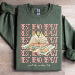 Green sweatshirt with "Rest, Read, Repeat" and "poolside reader club" text and illustrations.