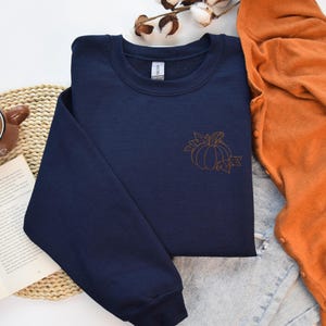 a blue shirt with a pumpkin on it next to a pair of glasses