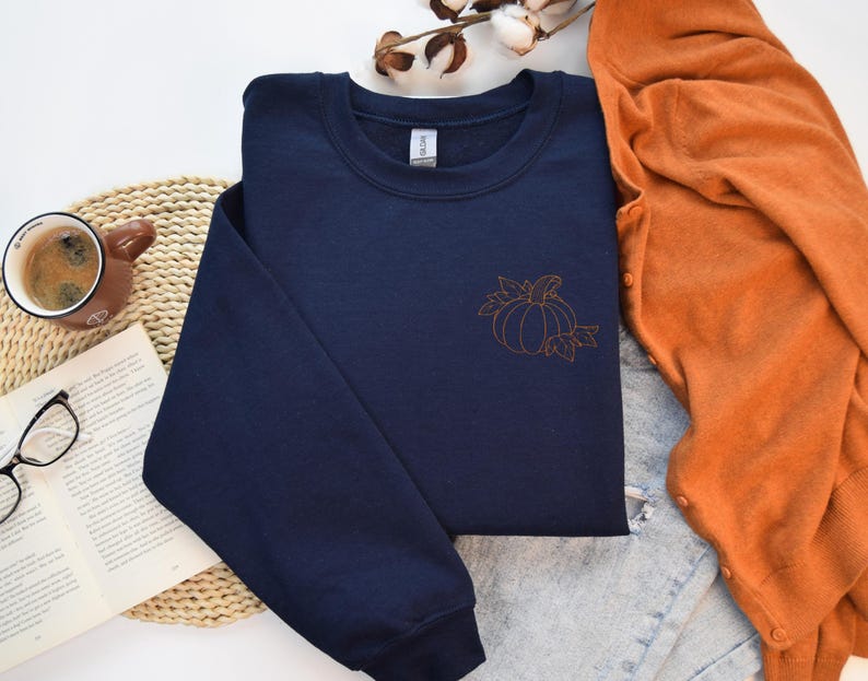 a blue shirt with a pumpkin on it next to a pair of glasses