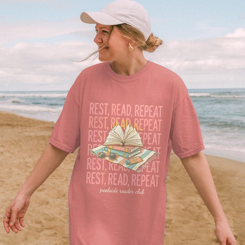 Coral t-shirt with stacked books, glasses, and text "REST, READ, REPEAT".