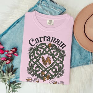 Pink t-shirt with Carranam Celtic knot design, feathers, and text.