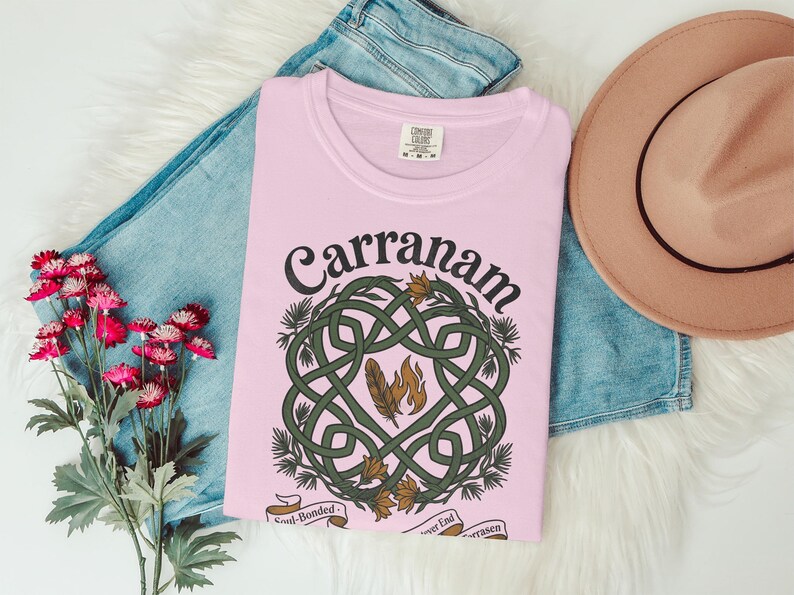 Pink t-shirt with Carranam Celtic knot design, feathers, and text.