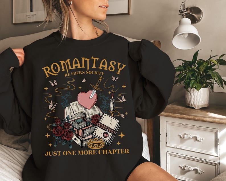 a woman wearing a black sweatshirt with a book and heart on it