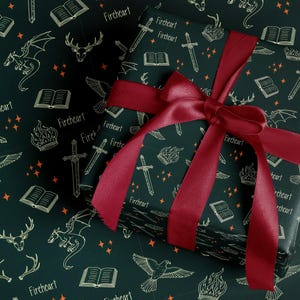a gift box with a red ribbon tied around it, set against a dark green background with a repeating pattern of white illustrations of a dragon, a book, a sword, and a crown.
