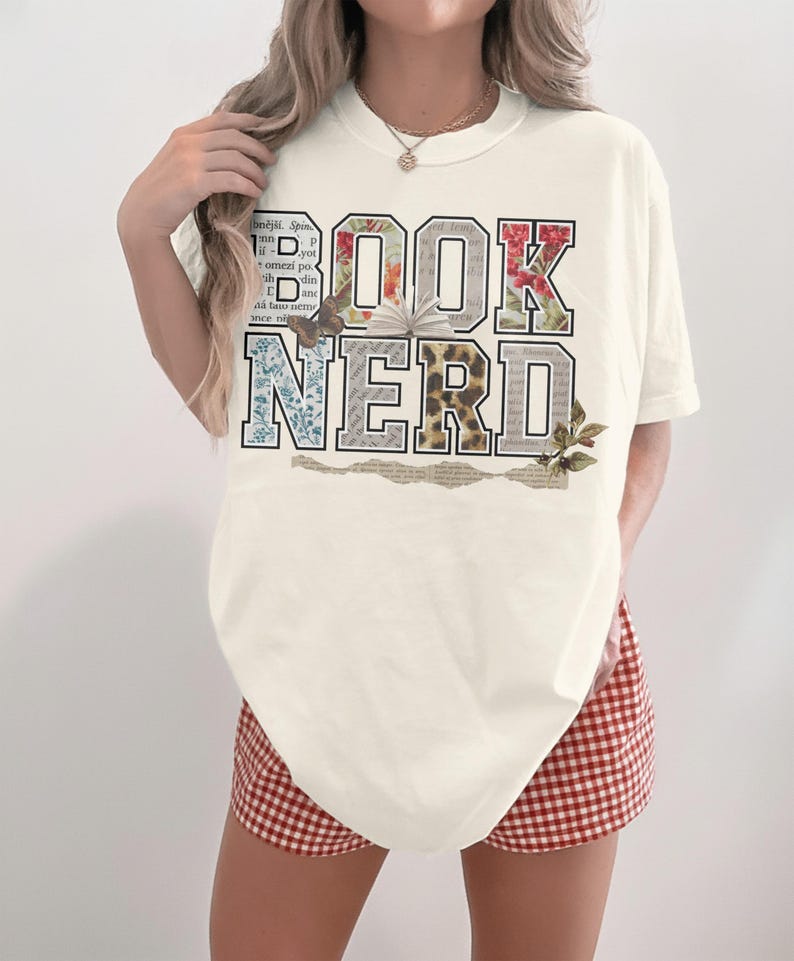 Cream t-shirt with "BOOK NERD" text graphic featuring floral and text patterns.