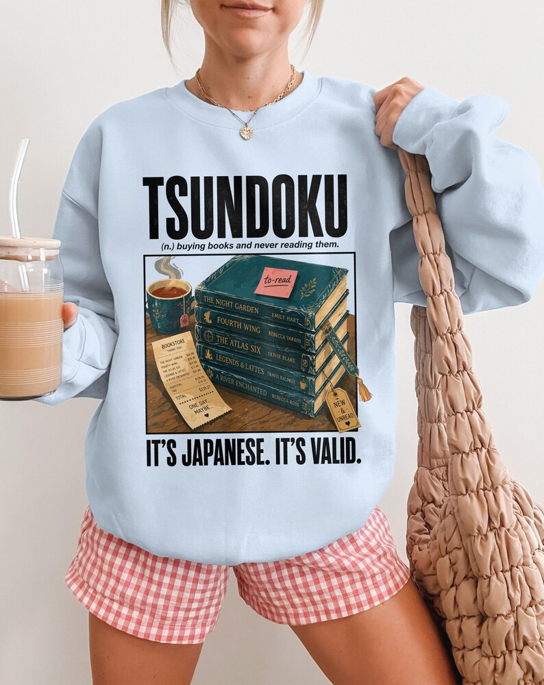 Light blue sweatshirt with "TSUNDOKU" and book stack with receipt.