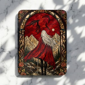 May include: A rectangular e-reader case featuring a stained glass style illustration of a long-haired figure in a red cloak standing before a mountain landscape. The scene includes flying dragons, a full moon, and a decorative floral border.