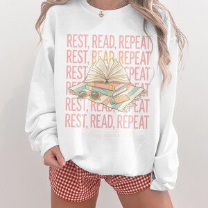 Sweatshirt with "REST, READ, REPEAT" and a stack of books.