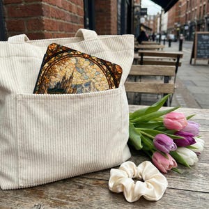 Cream corduroy tote bag with stained glass castle insert, tulips, and scrunchie.