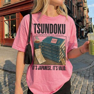 Pink t-shirt with "Tsundoku" and a stack of books labeled "to-read".