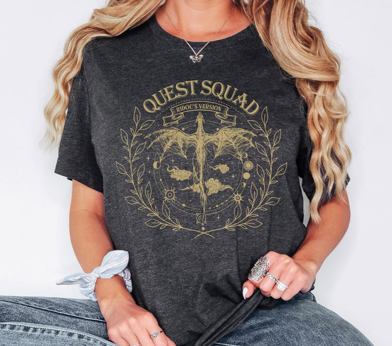 a woman sitting on a chair wearing a t - shirt that says quest squad