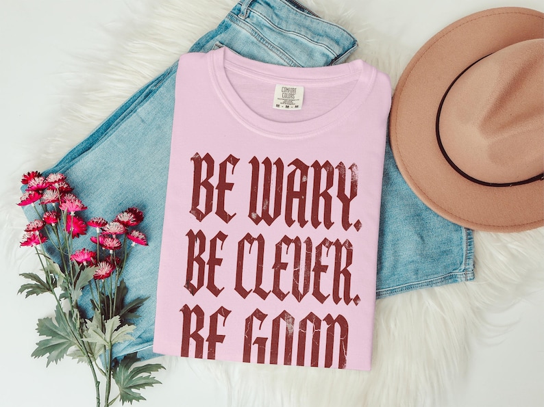 Pink t-shirt with "Be Wary Be Clever Be Good" text.
