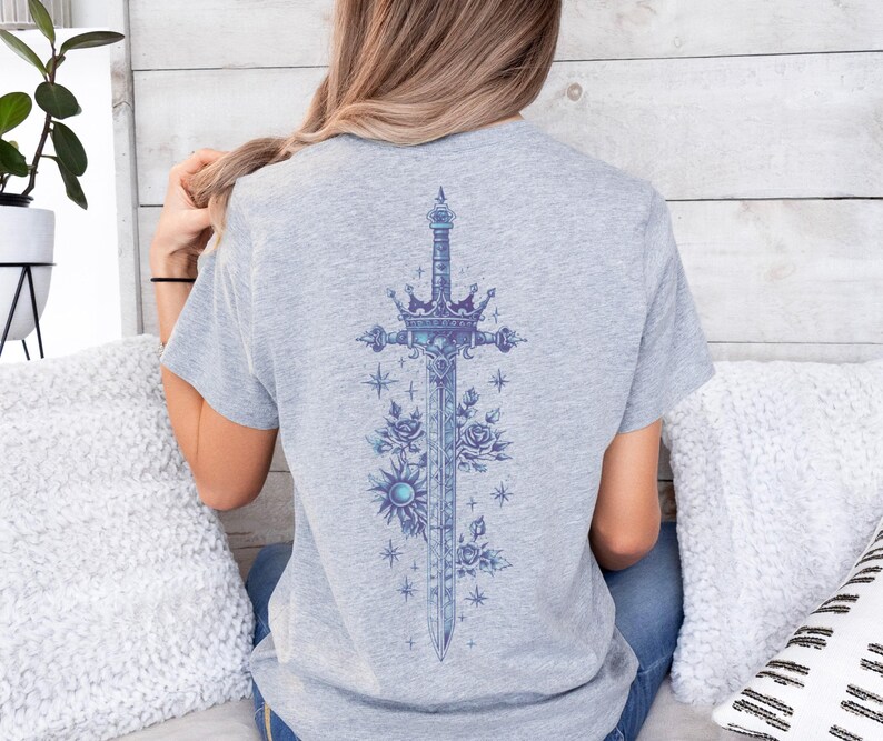 a woman sitting on a bed wearing a t - shirt with a cross on it