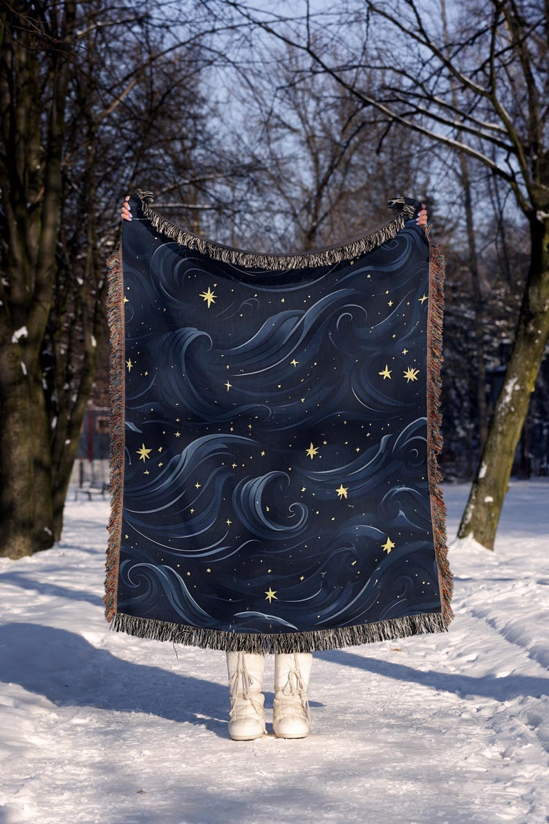 a person standing in the snow holding a blanket