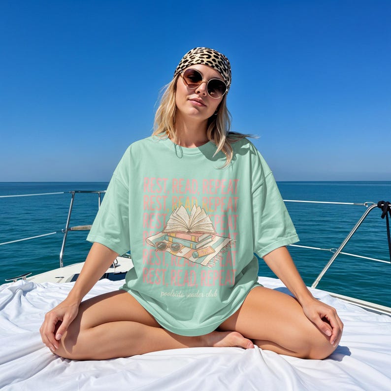 Woman wearing a mint green t-shirt with "read, sleep, repeat" text sitting on a boat.