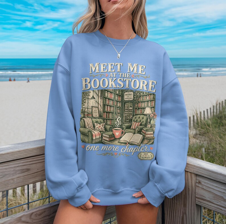 Light blue sweatshirt with "Meet Me at the Bookstore" text and book illustrations.