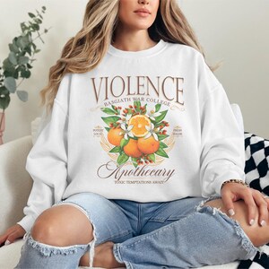 a woman sitting on a couch wearing a white sweatshirt