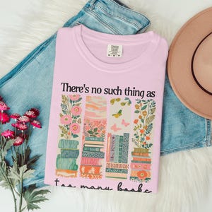 Pink t-shirt with floral and book design and text "There's no such thing as too many books."