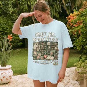 Light blue t-shirt with "MEET ME AT THE BOOKSTORE" and library illustration.