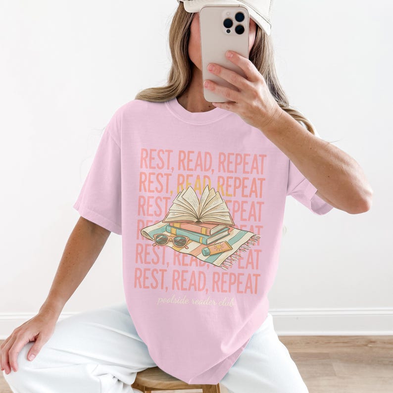 Pink t-shirt with "REST, READ, REPEAT" text and open books illustration.