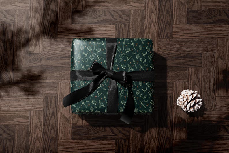 A green gift box with a black ribbon tied around it, placed on a wooden surface.