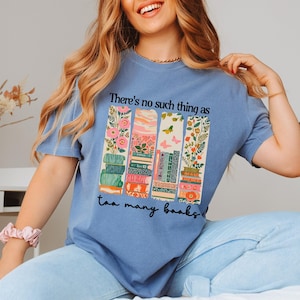 Blue t-shirt with "There's no such thing as too many books" and floral book stack design.