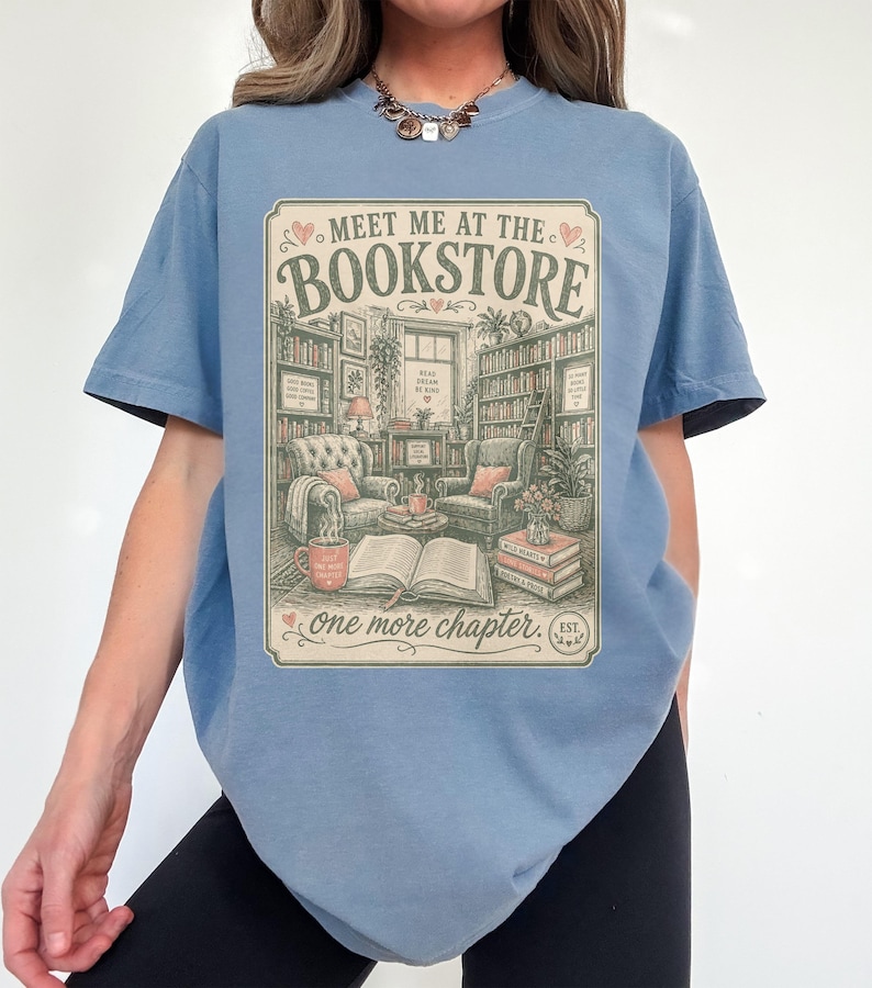 T-shirt with "Meet Me at the Bookstore" text and cozy reading scene.