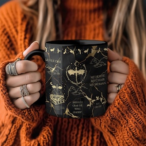 Könnte beinhalten: Schwarze Keramik-Tasse mit goldenen Akzenten und Text. Die Tasse hat ein detailliertes Design mit einer Fledermaus, Wolken und Text, der "SILVER ONE", "MY HOUSE MY CHAIR MY WOMAN", "SHOULD I GRAB THE WING LEADER?" und "FLY OR DIE" lautet.